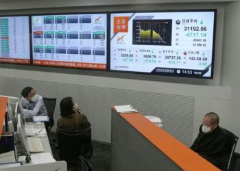 Empleados mirando monitores que muestran el promedio de acciones Nikkei de Japón, que ha tenido una caída récord en el precio de cierre, en la Bolsa de Valores de Nagoya